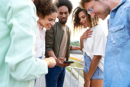 Happy group of friends watching something on phoneの写真素材