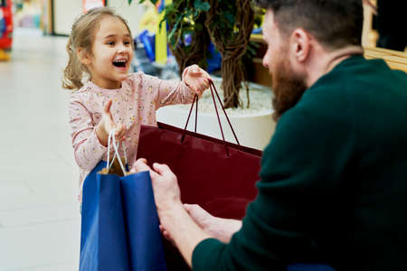 Daughter gives her dad bags full of shoppingの写真素材