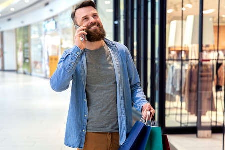 Happy man calling while shopping at the mallの写真素材