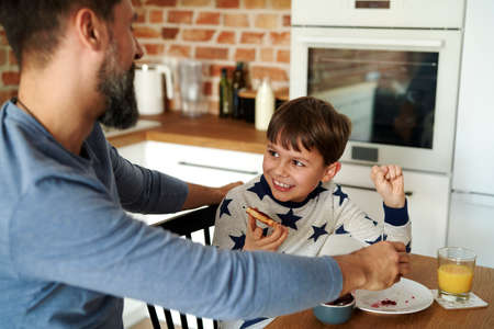 Mid adult man having breakfast with his sonの写真素材