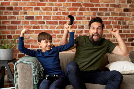 Father and son have fun while playing video gameの写真素材