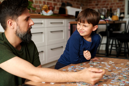 Father and son sitting and solving jigsaw puzzleの写真素材