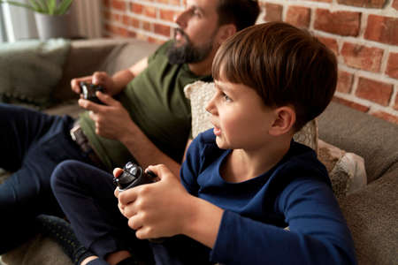 Father and son playing video game at home