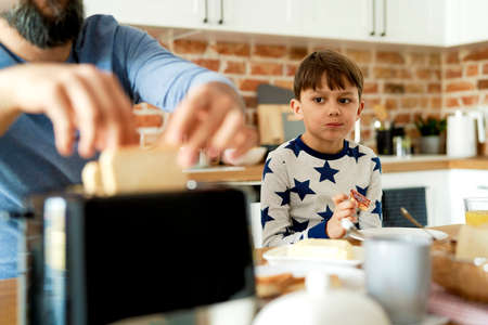 Close up of father and son eating breakfast in the kitchenの写真素材