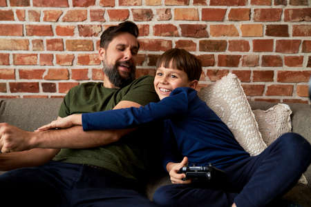 Playful son playing video game with father
