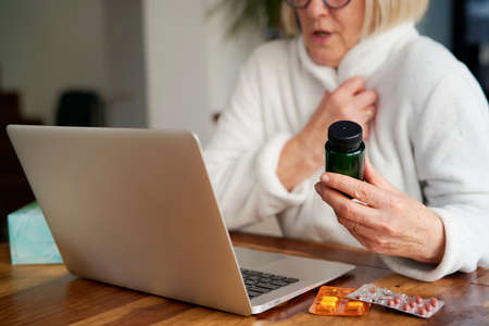 Close up of sick woman consults doctor online using a laptopの写真素材