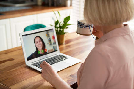 Rear view of senior woman during video conference with daughter