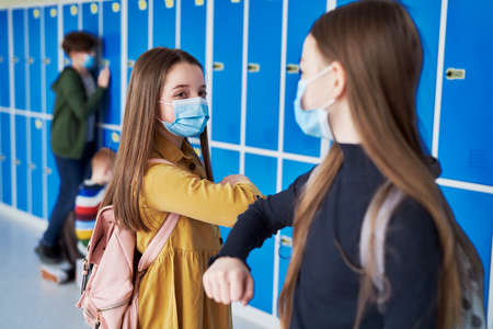 Girls wearing protective masks and having an elbow greetingの写真素材