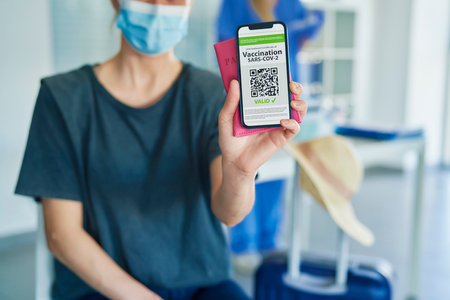 Close up of woman holding phone with digital vaccination cardの写真素材
