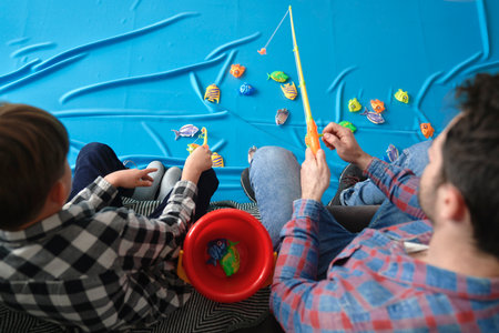Top view of child with father playing fishing at home