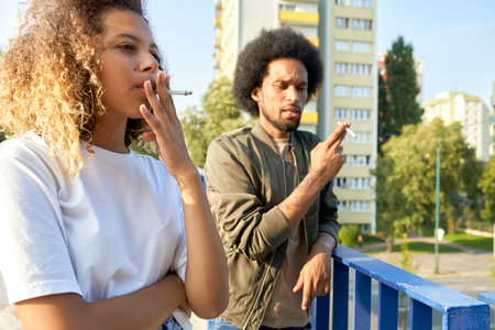 Two young people standing and smoking cigaretteの写真素材