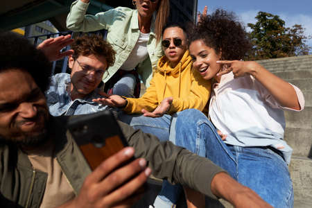Young people gesturing and doing selfie together outdoors