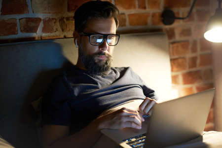 Man working on his laptop in the bed at night