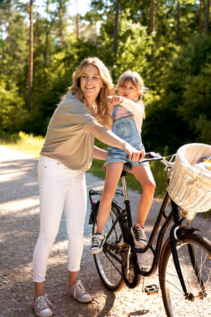 Mother and daughter with bicycle in the forestの写真素材