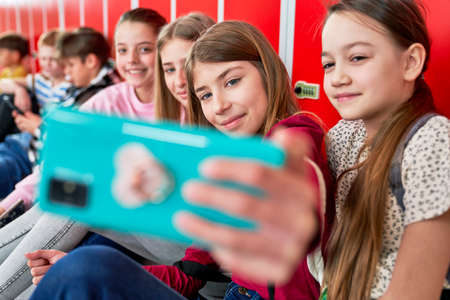 Schoolgirls make smiling photos on the corridor