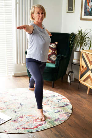 Senior woman doing balance exercise at homeの写真素材