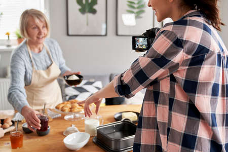 Young woman helping her vlogging motherの写真素材