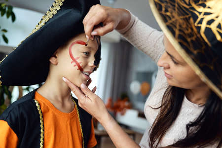 Mom preparing little boy for Halloween party
