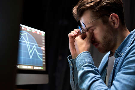 Young adult man is tired of work with financesの写真素材