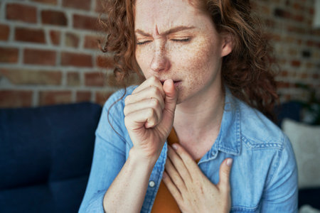 Caucasian red head woman coughing and having lungs infectionの写真素材