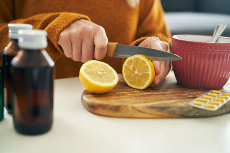 Unrecognizable woman cutting lemon for winter teaの写真素材