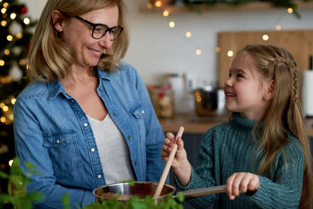 Happy grandma and little granddaughter cooking together in the kitchenの写真素材