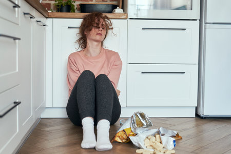 Young caucasian woman eating greedily some snacksの写真素材