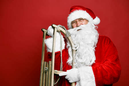 Caucasian Santa Claus with sled on red backgroundの写真素材