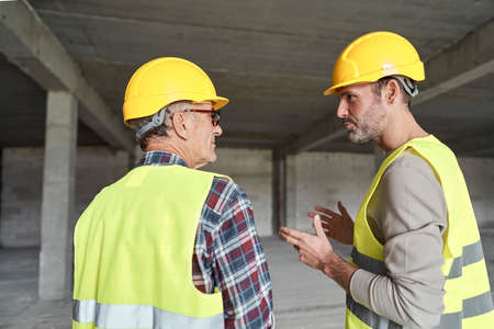 Back view of two caucasian engineers discussing on construction siteの写真素材