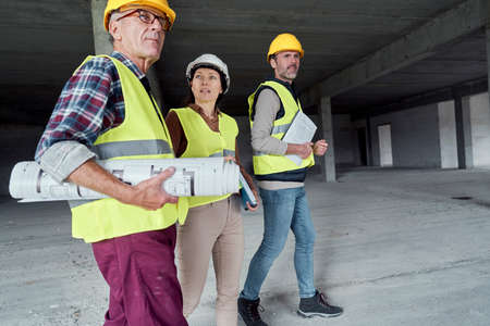 Three busy caucasian engineers walking across the construction siteの写真素材