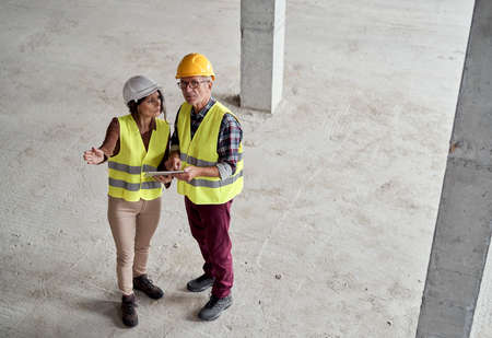 High angle view video of male and female caucasian engineers discussing and pointing on the construction siteの写真素材
