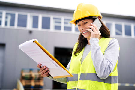 Caucasian mature woman in front of warehouse talking by mobile phoneの写真素材