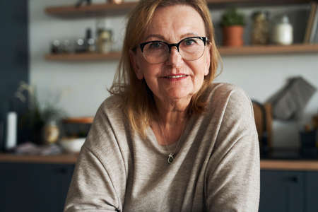Portrait of caucasian senior woman leaning in the kitchen island