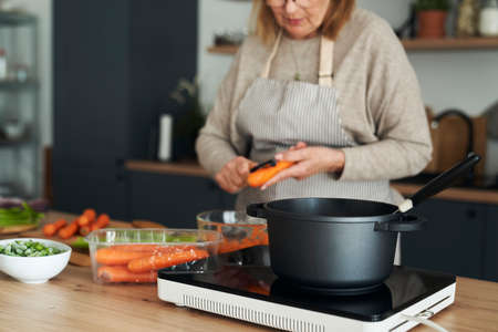 Close up of caucasian senior woman preparing meal in the kitchen islandの写真素材