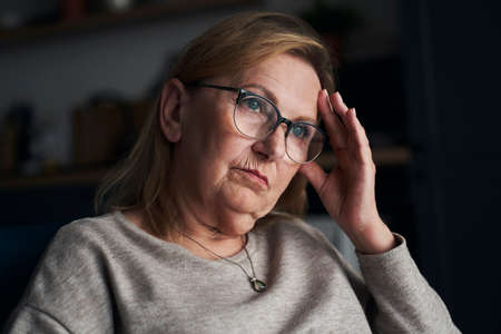 Thoughtful caucasian senior woman sitting and looking away