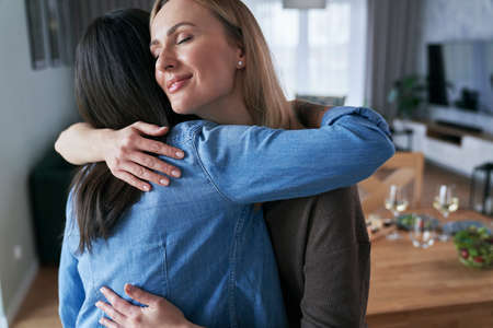 Two caucasian women embracing each other at homeの写真素材