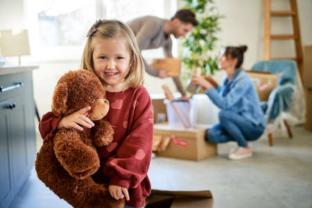 Portrait of little girl holding teddy bear in new houseの写真素材