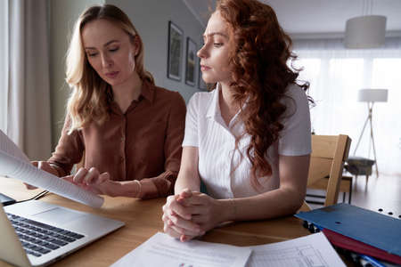Two woman analyzing document at home officeの写真素材