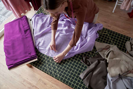 Caucasian tailor cuts out the template on the tableの写真素材