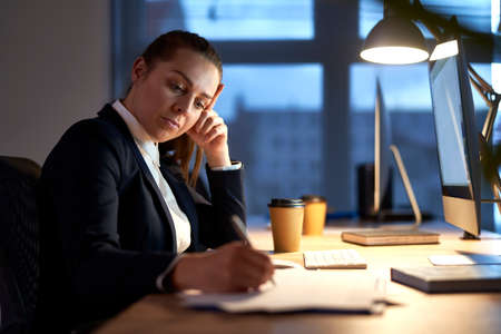 Caucasian adult woman working to late at the officeの写真素材