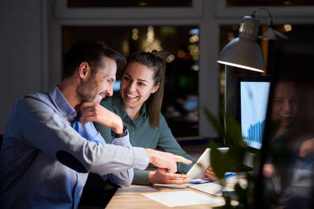 Caucasian woman and man working late together at the officeの写真素材