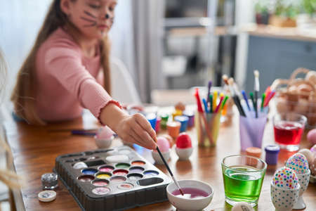Caucasian girl decorating easter eggs in the domestic kitchenの写真素材