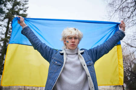Caucasian man holding Ukrainian flag stretched and looking at cameraの写真素材
