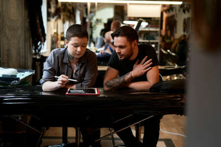 Caucasian artist talking about new project of tattoo with customerの写真素材