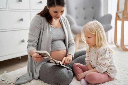 Caucasian woman in advanced pregnancy browsing ultrasound scan with her elementary aged daughter