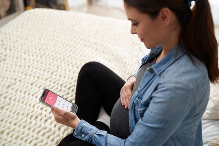 Pregnant caucasian woman using mobile app on smartphone