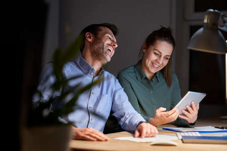 Caucasian adult woman and man working late together at the office