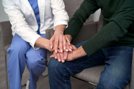Close up of caucasian doctor and patient holding hands