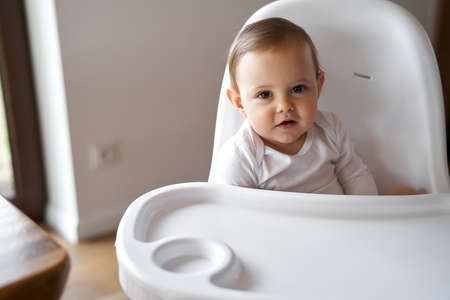 Portrait of cute little baby siting in high chair at homeの写真素材