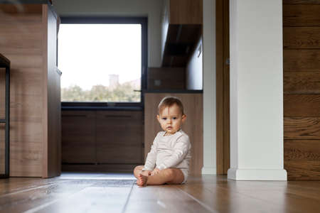 Portrait of little baby sitting in the floor at homeの写真素材